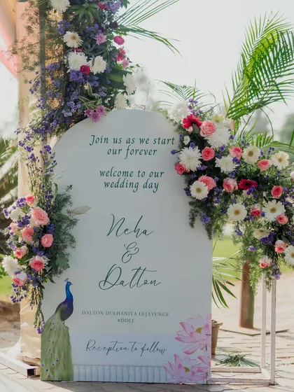 The elegant welcome sign, framed by beautiful fresh flowers, greets guests as they arrive, setting the tone for a beautiful celebration.