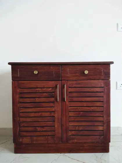 A frontal view of the slatted shoe rack, showing its compact design and classic brass knobs.