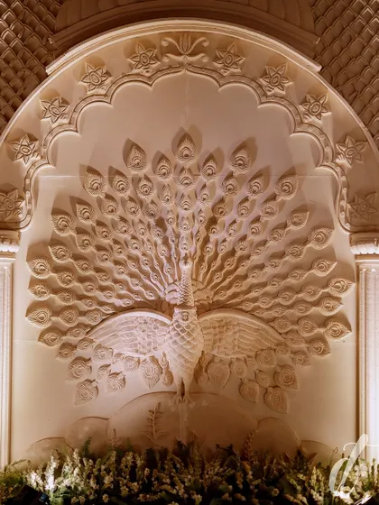 A magnificent hand-carved panel of a peacock, a symbol of grace and beauty in Indian culture. This custom piece served as a breathtaking backdrop and a major focal point for the event.