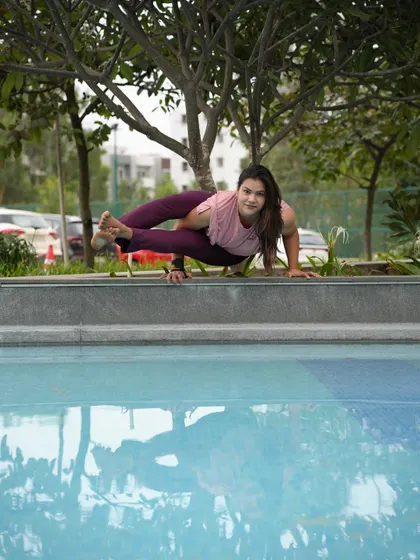 Astavakrasana (Eight-Angle Pose) by the pool. This pose looks complex, but with the right technique of hooking the legs and shifting weight, it becomes an accessible and empowering arm balance.