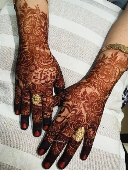 A close-up of the rich henna stain, showcasing the bride's name delicately woven into the floral design on her palm.