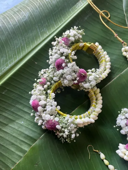 A close-up of the floral bracelets from the jasmine bud set. The design is built on a sturdy base and decorated with baby's breath and pink flowers.