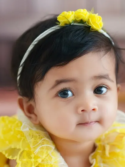 A sweet and simple close-up portrait of a baby girl. The soft, out-of-focus background and the yellow floral headband draw all the attention to her beautiful eyes.