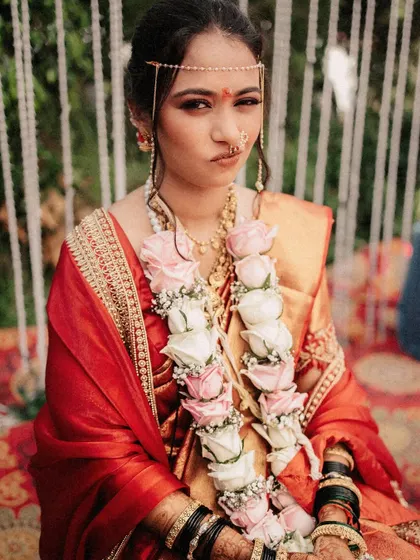 A playful portrait of the bride during the ceremony, wearing a garland of pink and white roses.