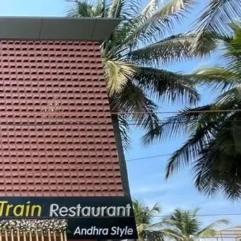 An angled view of the Kritunga restaurant's exterior, showing how the modern brick facade contrasts with the surrounding natural elements like palm trees.