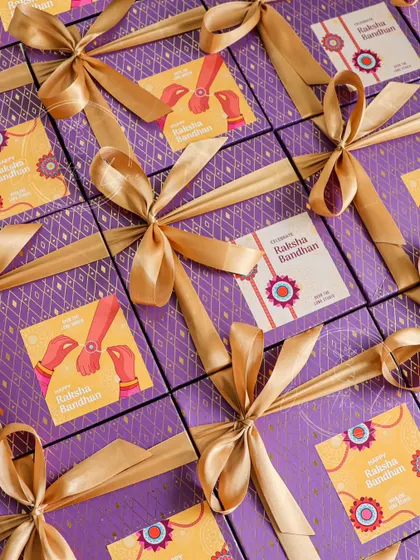 A grid of my beautifully wrapped Rakhi hampers, ready to be sent out. The purple and gold packaging adds a touch of royalty to your festive gifting.