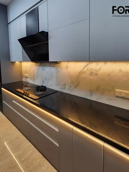 A linear kitchen featuring handleless cabinets and a striking black countertop with integrated lighting. The marble-effect backsplash adds a touch of luxury, while the layout keeps everything within easy reach.