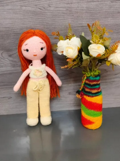 Here is the same doll with long red hair, standing next to a vase. She is very elegant.