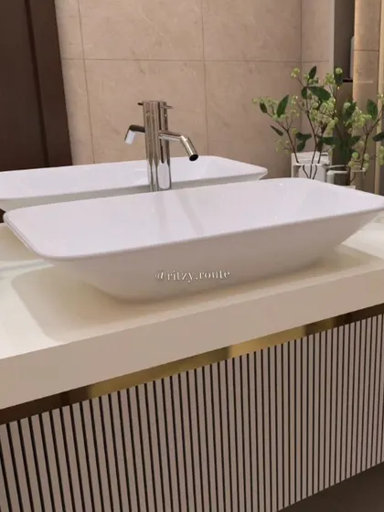 A close-up of the bathroom bliss. This shot highlights the clean lines of the dual vessel sinks and the texture of the vertically striped vanity, accented with a thin gold line for a touch of modern elegance.