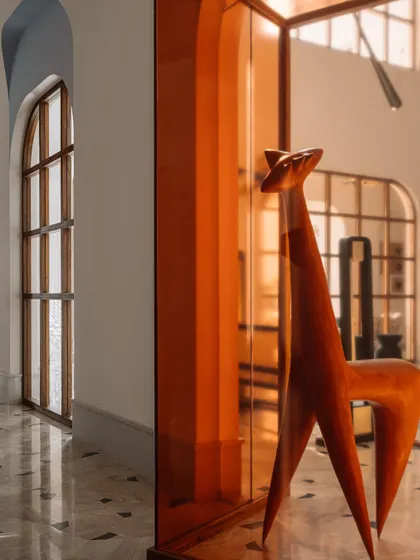 A diptych showing the arched windows of the galleria and a close-up of the wooden sculpture peeking out from its amber-colored glass case.