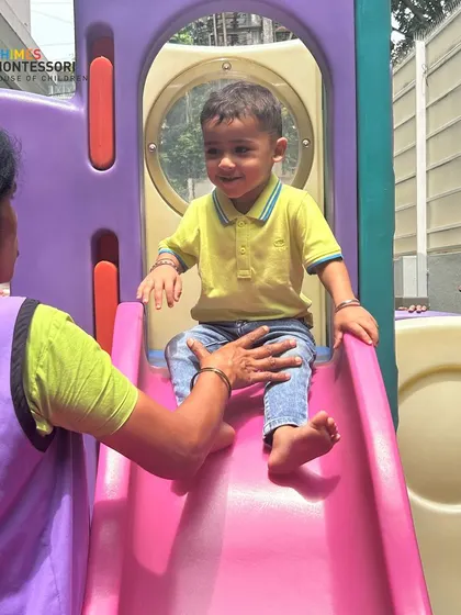 An adult gently guides a new child on the slide, providing the support and reassurance needed to build confidence.