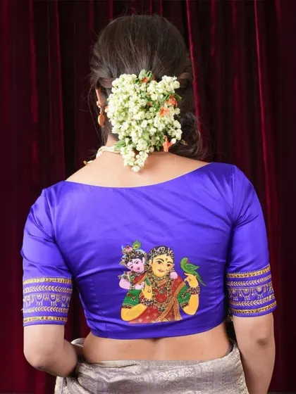 The back of this royal blue blouse features a hand-painted depiction of Yashoda and Krishna, making it a truly unique and artistic piece.