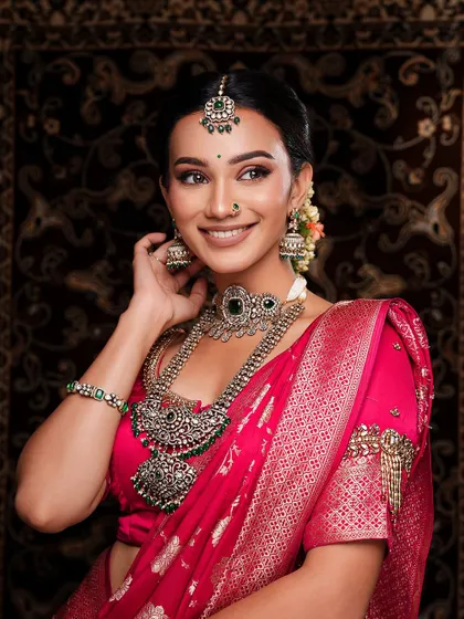 A radiant bride in a pink silk saree, adorned with silver jewelry with green stones. This look is a perfect blend of traditional and contemporary styles.