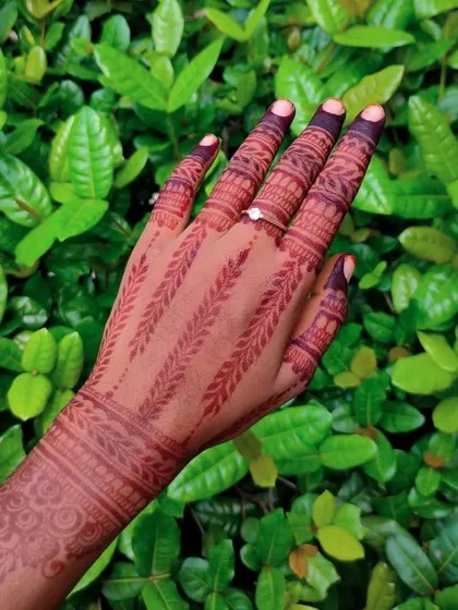 This design features delicate leafy vines running up each finger, creating a unique and nature-inspired look. The stain is a beautiful, warm brown against the green background.