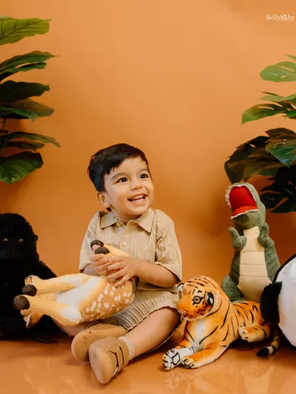 Welcome to the jungle! This little explorer is having a blast with his animal friends in this vibrant, nature-themed studio setup.