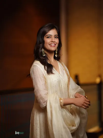 Capturing a moment of pure, natural joy. The subject's bright smile is the centerpiece of this portrait, complemented by the soft elegance of her white ethnic suit.