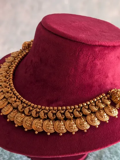 The Kaasu design necklace, shown here on a display, is a versatile piece that can be worn alone for a simpler function or layered with a haara for a full bridal look.