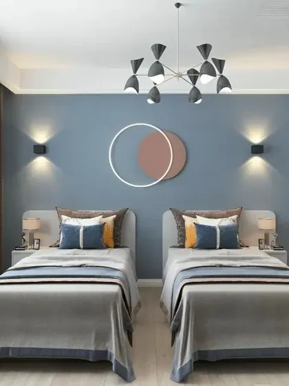 A modern bedroom with two single beds, featuring a cool blue accent wall and contemporary wall sconces. The open-frame shelving unit adds storage without visually cluttering the room.