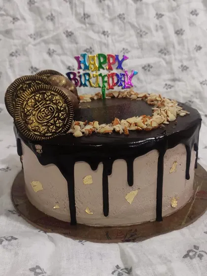 A classic combination of chocolate and almond, this drip cake is a crowd-pleaser. It features a rich chocolate drip, crunchy chopped almonds, and golden Oreo cookies for decoration.