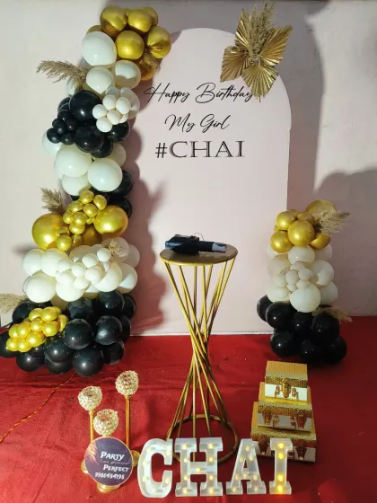 This black, white, and gold setup for Chai's 21st birthday is both modern and fun. The arching balloon garland frames a personalized backdrop, with a light-up name sign adding a special touch.
