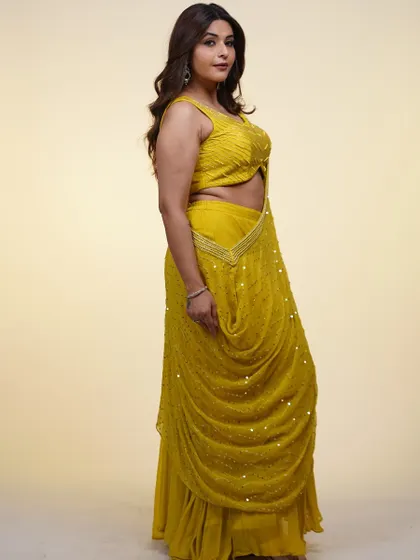 This yellow draped saree-style lehenga is perfect for a haldi or mehndi ceremony. The pearl detailing and unique silhouette offer a fresh take on traditional wear.