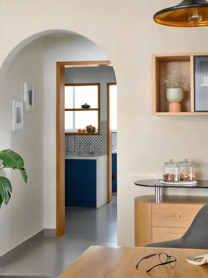 An arched entryway leads into the 'Cover me in Sunshine' kitchen, offering a glimpse of the royal blue cabinetry and patterned tiles.