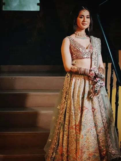 The bride poses on a staircase, showing off her stunning Abhinav Mishra lehenga for the Mehendi ceremony. The pastel colors and mirror work are perfect for a daytime event.