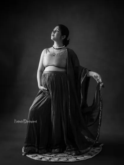 A dramatic and artistic black and white portrait. The lighting and pose create a timeless and powerful image of a mother looking towards the future.