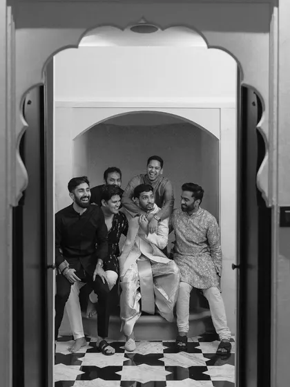 A fun, candid black and white shot of the groom with his groomsmen, capturing the camaraderie and excitement before the wedding.