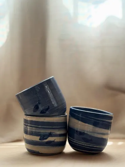 A stack of Blue Fish Tumblers. The marble clay technique ensures that no two cups are exactly alike, each with its own unique swirl of blue and white.
