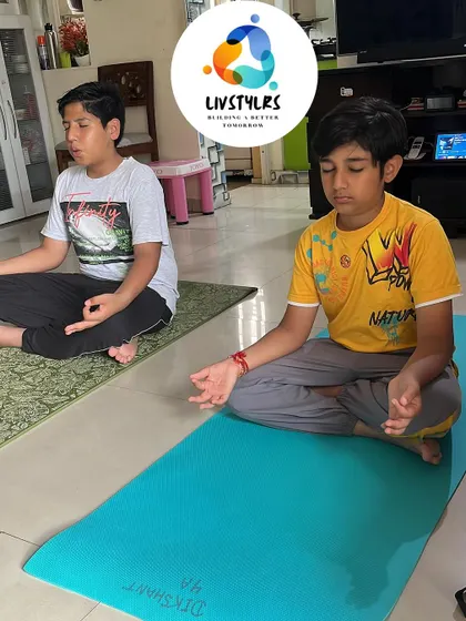 Two boys sit in meditation, learning the valuable skill of mindfulness from a young age. This practice helps improve focus and emotional regulation.