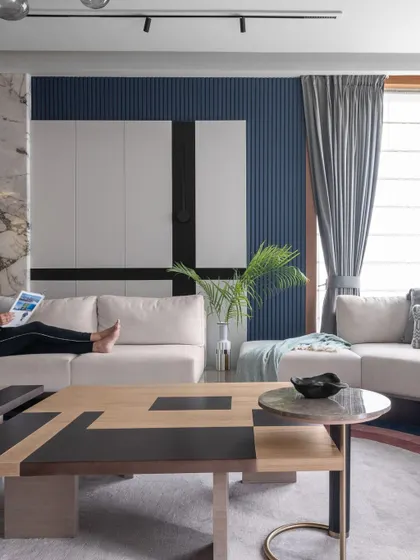 This angle captures a person relaxing in the space, emphasizing the comfort and livability of our design. The combination of a deep sofa, soft lighting, and curated decor creates a perfect spot for unwinding.