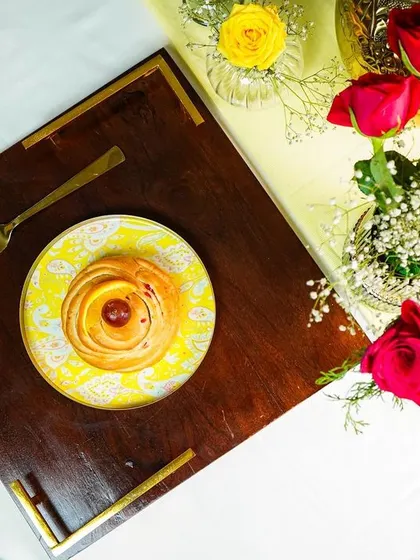 An overhead shot of a single place setting on a wooden tray, surrounded by fresh roses. This composition is elegant and romantic.