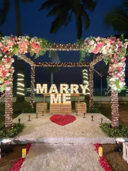 The complete proposal setup at night, with a heart made of rose petals, fairy lights, and marquee letters creating an incredibly romantic ambiance.