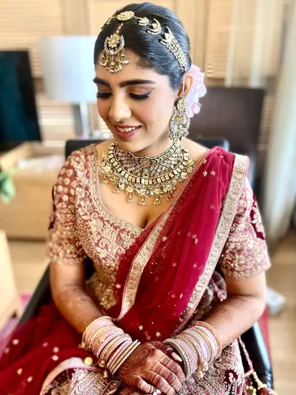 A royal bride in a beautiful red and maroon lehenga. I created a classic updo with a floral touch for her wedding day.