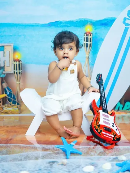This little rockstar is enjoying the beach vibes. The combination of a toy guitar and a surf-themed backdrop makes for a fun and unique birthday portrait.