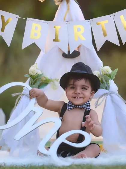 A big smile for the big ONE. Using props like this "One" sign and a classic teepee setup, I create timeless and joyful portraits to celebrate your baby's first birthday milestone.