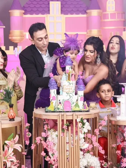 A grand celebration with the entire family. This shot captures the excitement of the cake cutting, complete with confetti and applause, at an elaborate princess castle themed party.