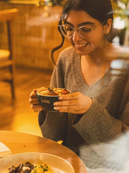 A lifestyle shot of a customer enjoying a warm drink in a cafe. Capturing genuine moments like this helps create a relatable and inviting brand image.