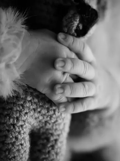 An artistic macro shot of a baby's hands, showing the delicate texture of their skin and the way they hold on.