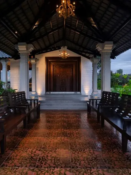 The grand entrance of the classical farmhouse, with an inviting porch furnished with traditional wooden benches.
