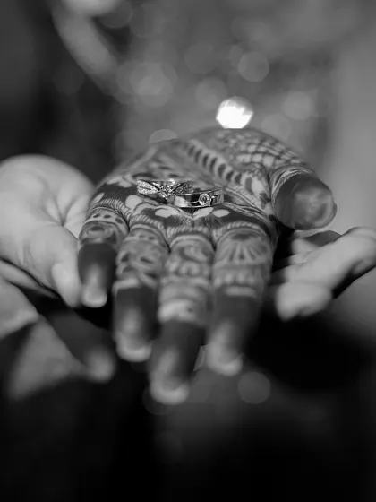 A creative black and white collage focusing on the engagement rings held in the bride's henna-adorned hand.