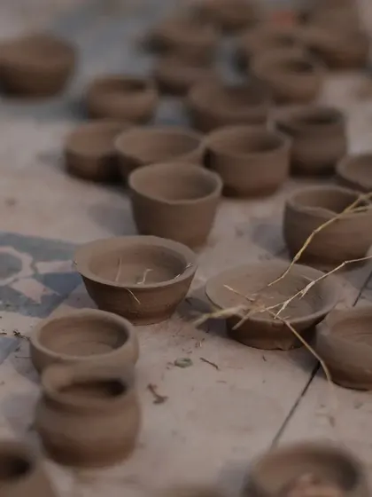 A collection of small, hand-molded clay pots made by children during a pottery session.