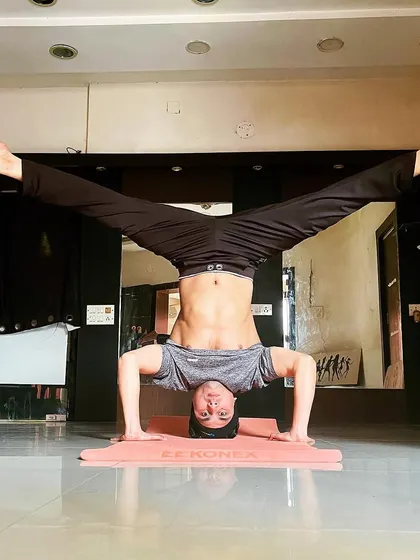 From the tripod headstand, I demonstrate a wide-legged variation, which challenges balance and hip flexibility.