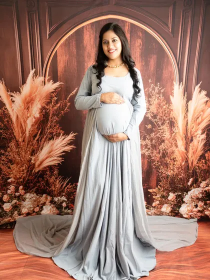 A simple and elegant portrait in a grey long-sleeved gown. The rustic, warm-toned backdrop provides a beautiful contrast.