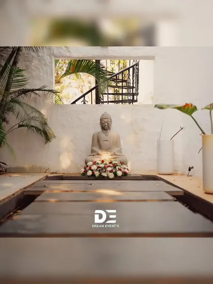 Creating a tranquil corner for a Haldi ceremony. A serene Buddha statue is adorned with a garland of white and red roses, blending spiritual calmness with celebratory aesthetics.