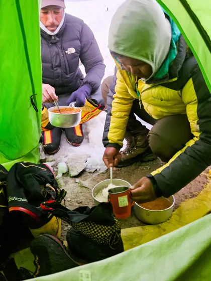 Preparing dal and chawal inside a tent during our Kang Yatse expedition. We manage all logistics, including providing hot, nutritious meals to keep you fueled at high altitude.