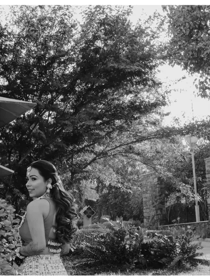 A classic black and white portrait of the bride in a garden, looking back at the camera with a gentle smile.