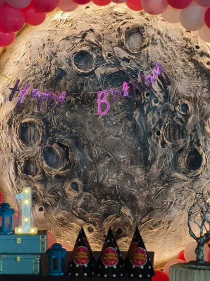 A close-up of the stunning moon backdrop for a first birthday. The detailed texture of the moon, combined with the pink balloon garland, shows the unique and conceptual decor I can create.