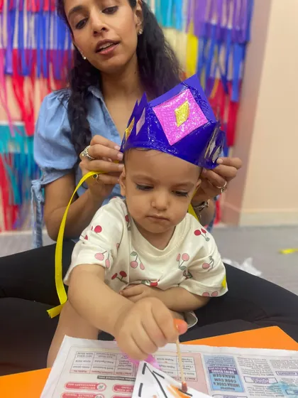 A mother helps her son wear a paper crown, a fun reward after a creative craft session.